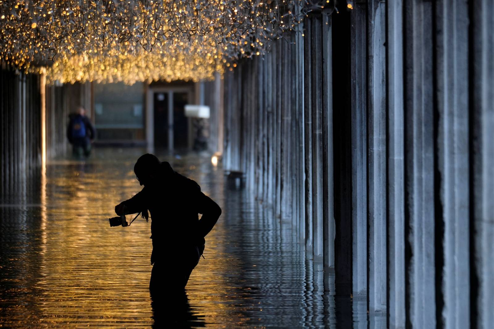 A man wades through a flooded street during high tide in Venice