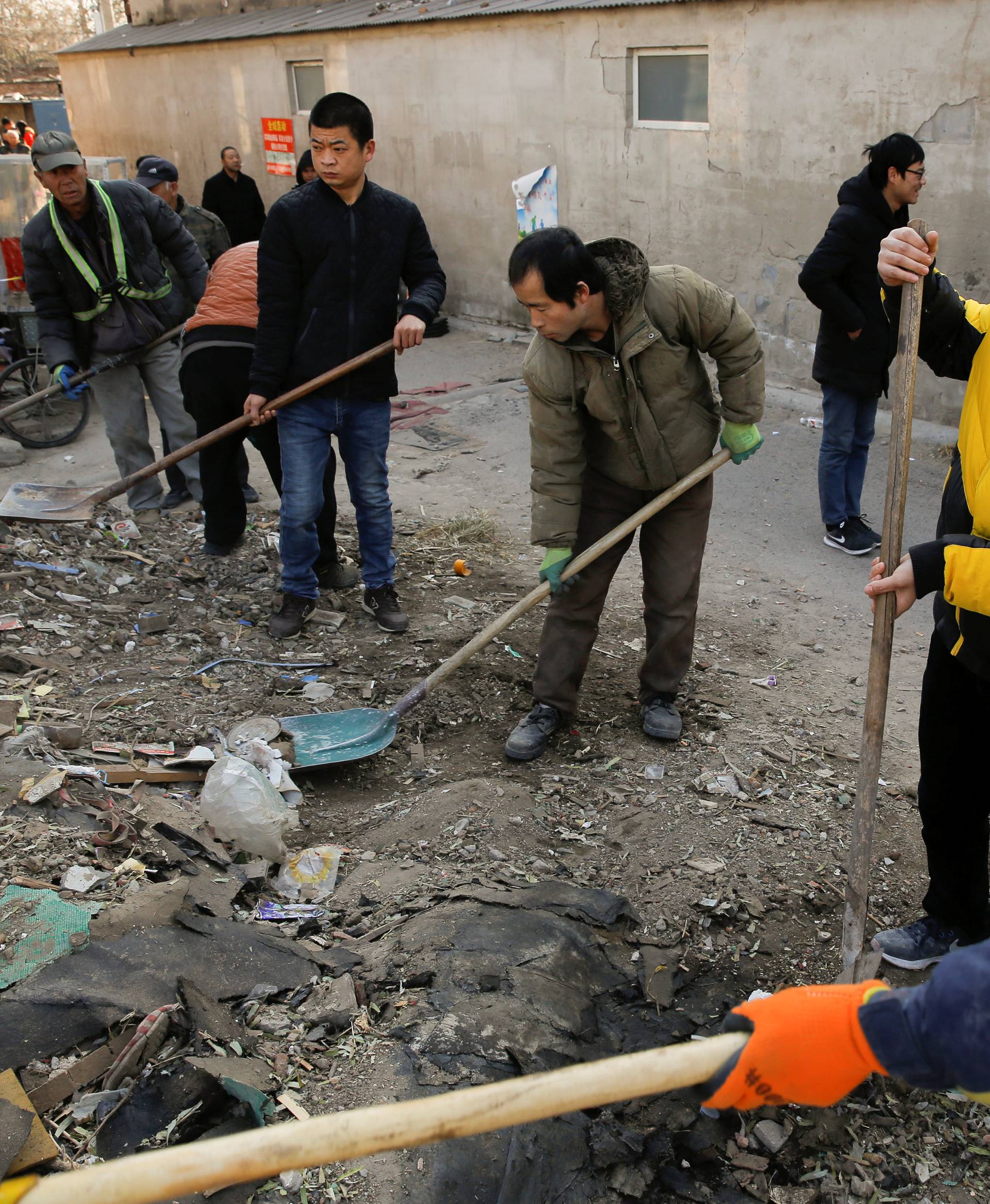 Men shovel debris in Beijing's Baiqiangzi village, which is mainly inhabited by migrant workers.