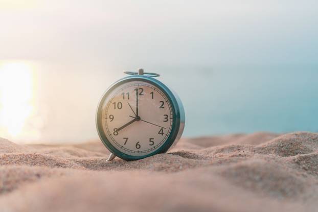 Selective focus of alarm clock with nature background.