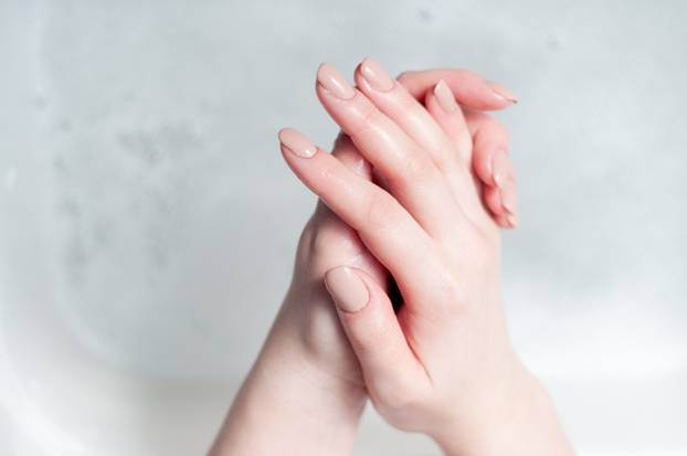 woman washes her hands over water with foam