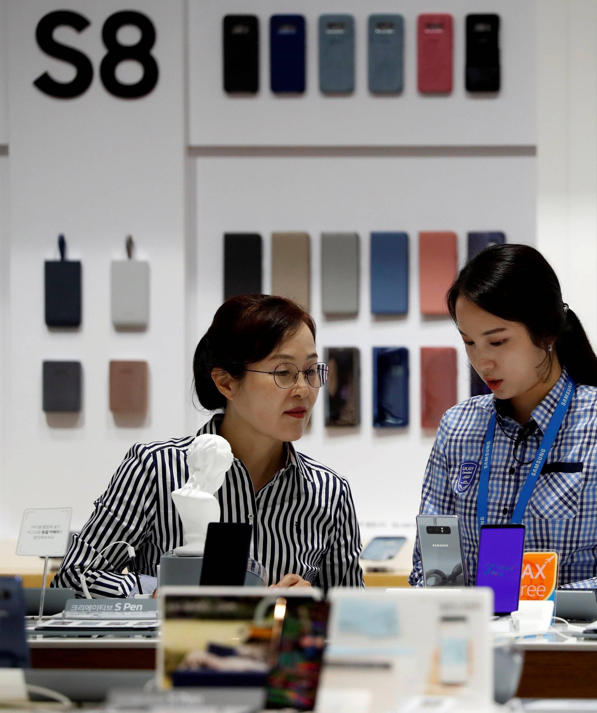 An employee helps a customer purchase a Samsung Electronics' Galaxy Note 8 at its store in Seoul