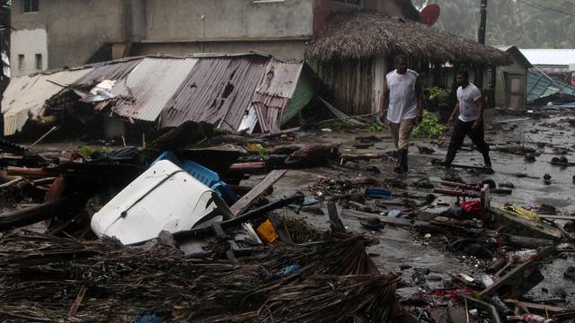 People walk past debris as Hurricane Irma moves off from the northern coast of the Dominican Republic, in Nagua