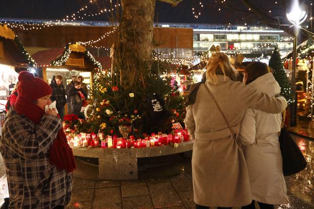 People mourn beside flowers and candles placed at the Christmas market at Breitscheid square in Berlin