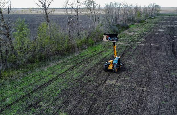 Worker uses a remote control to operate a demining machine made of tractor and armoured plates from destroyed Russian military vehicles in a field near the village of Hrakove