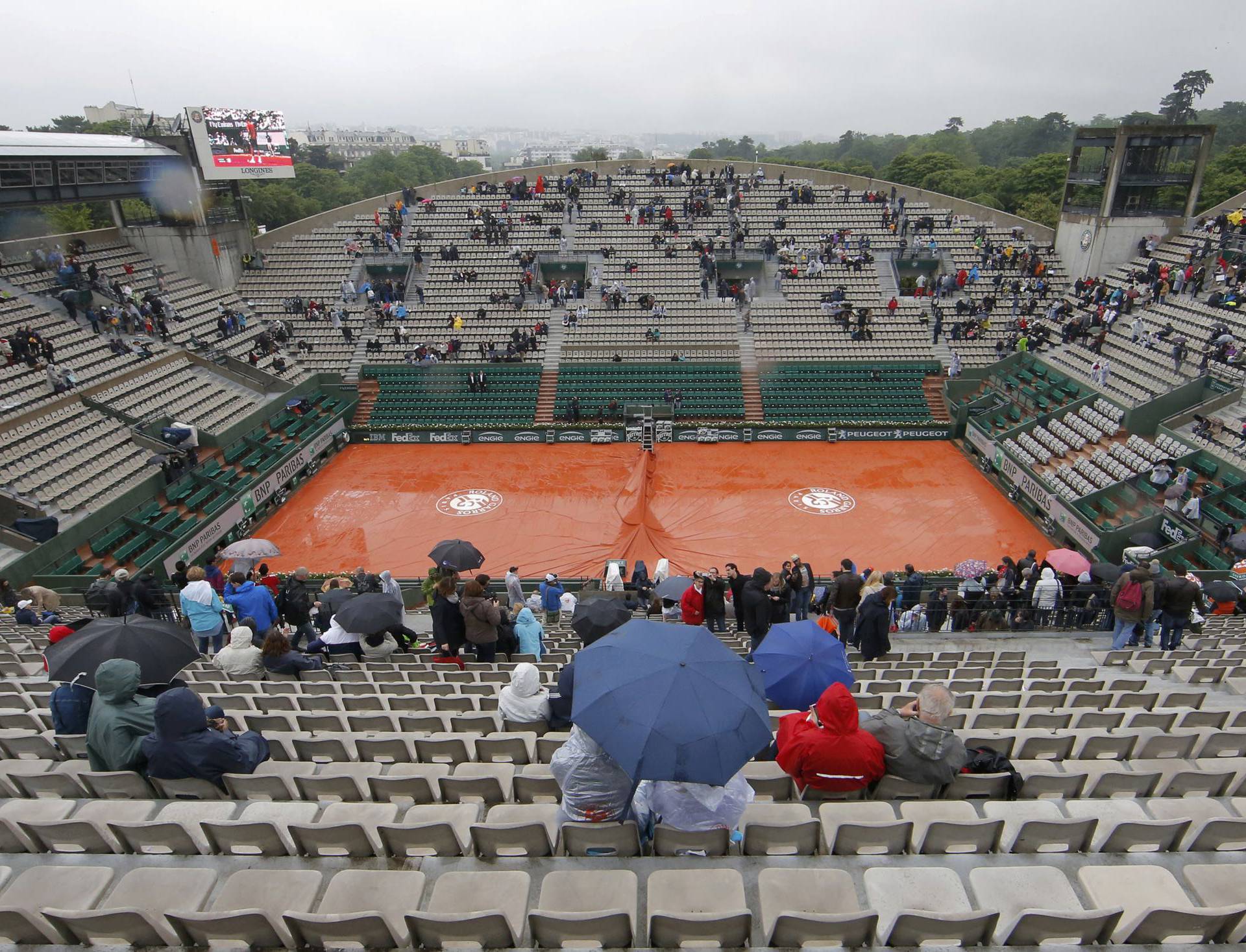 Tennis - French Open - Roland Garros - Spectators protect themselves from the rain 