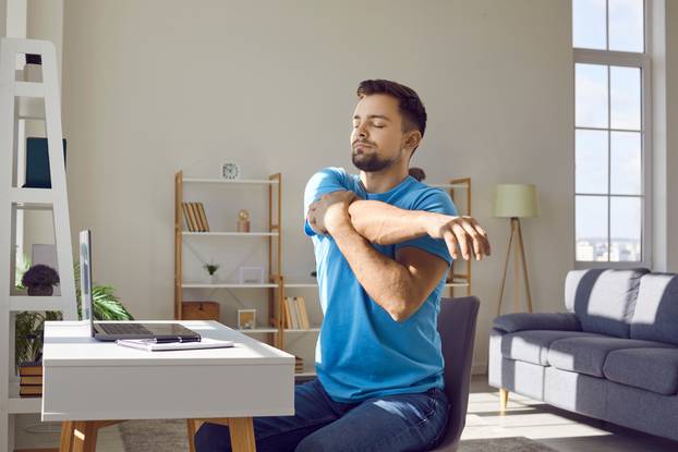 Man,Stretches,During,Work,Break.,Young,Man,In,Blue,T