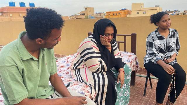 A Sudanese family sits on the roof-top of their house during the conflict in Khartoum