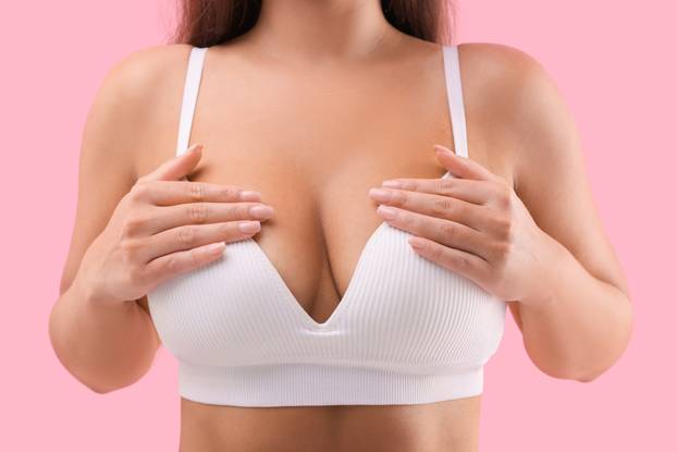 Woman with beautiful breast on pink background, closeup