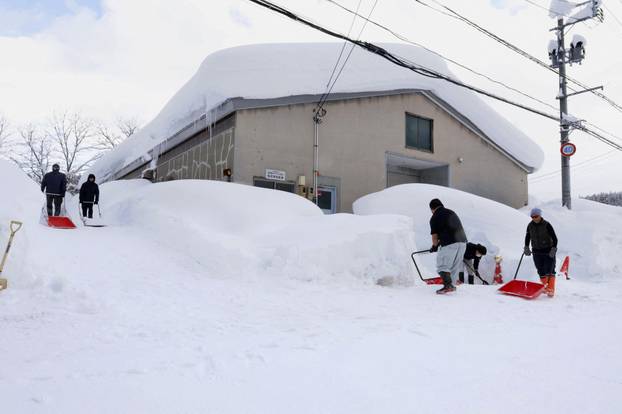 People remove snow near a house in Aomori, northeastern Japan, as heavy snow continues to hit the region