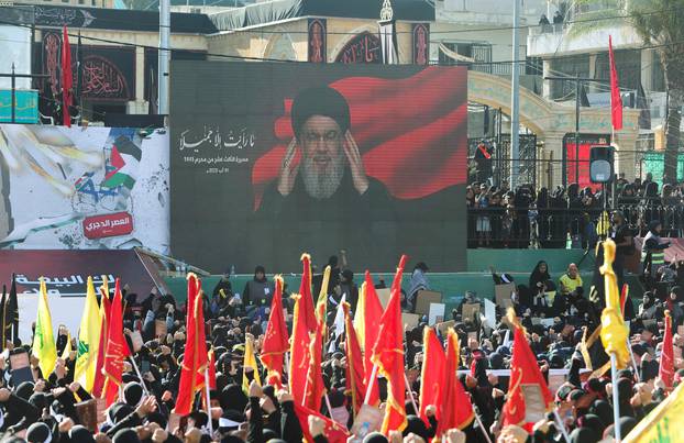 Supporters of Lebanon's Hezbollah leader Sayyed Hassan Nasrallah listen to him as he addresses them through a screen