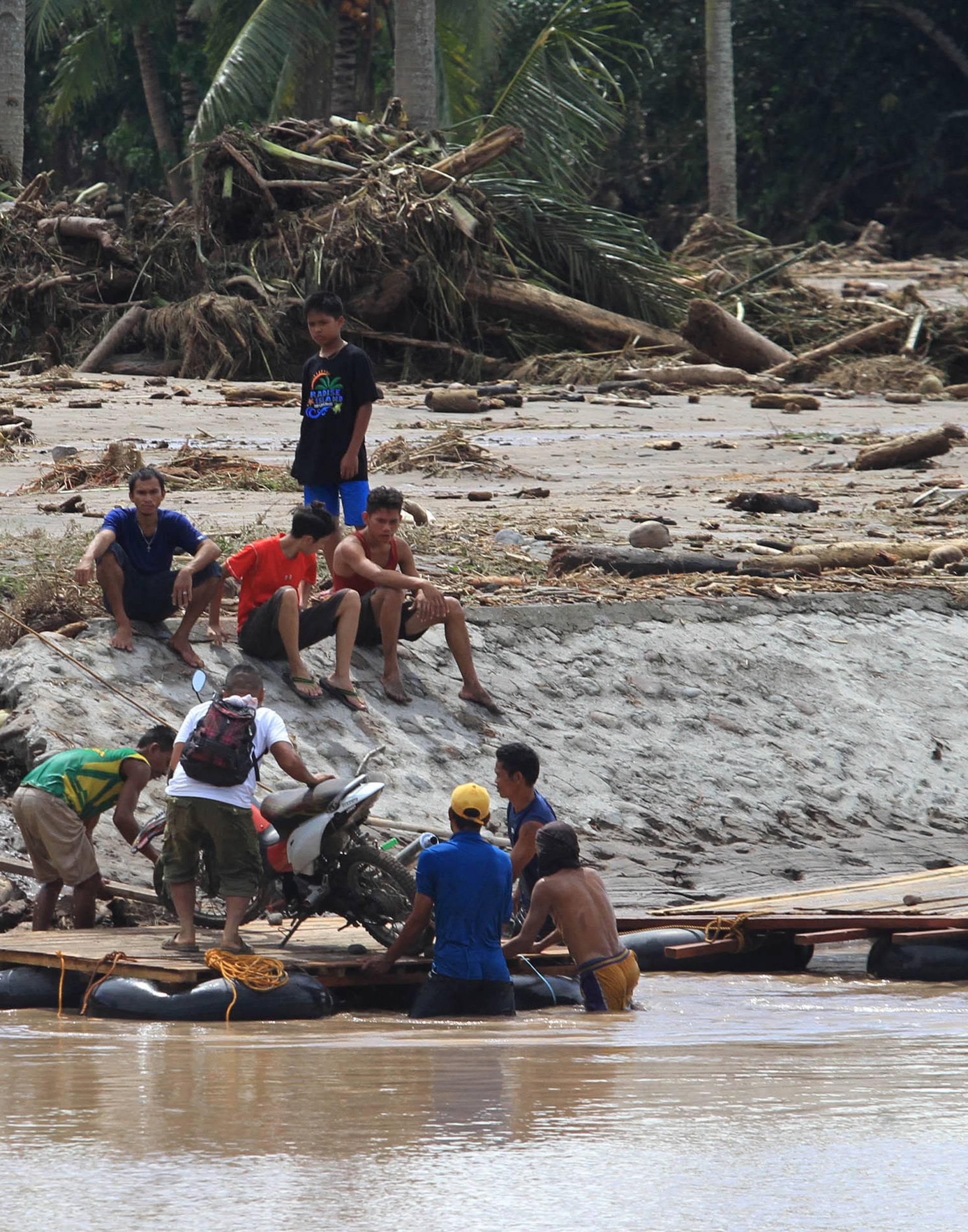 Man and his motorcycle are transported on a makeshift raft after a bridge was destroyed by flash floods in Salvador, Lanao del Norte