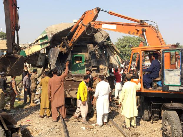 Rescuers workers use heavy machinery on the car of a train which crashed outside Karachi,