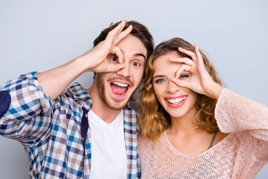Head shot portrait of funky cheerful couple gesturing ok sign ar