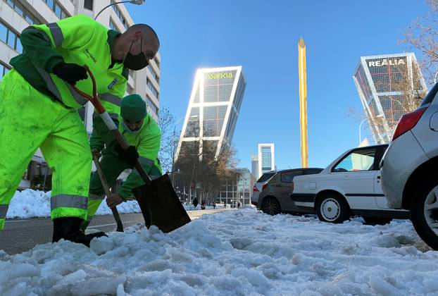 Workers shovel snow in front of headquarters of Spanish lenders Bankia after heavy snowfall in Madrid
