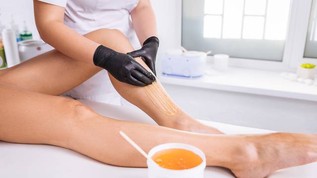 Professional master of wax depilation providing service for client