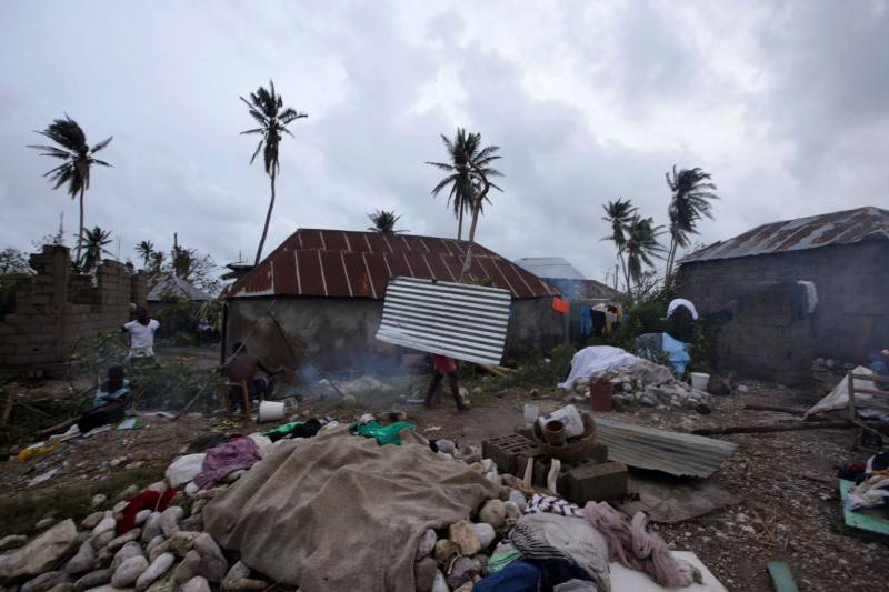 A woman carries a tin sheet after Hurricane Matthew in Les Cayes, Haiti