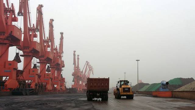 FILE PHOTO: Trucks drive inside an iron ore dump site at the Huanggang Terminal of Qingdao Port, in Qingdao