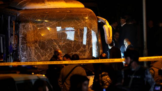 Police officers inspect a scene of a bus blast in Giza