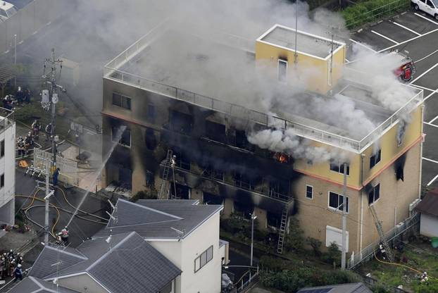 An aerial view shows firefighters battling fires at the site where a man started a fire after spraying a liquid at a three-story studio of Kyoto Animation Co. in Kyoto, western Japan, in this photo taken by Kyodo