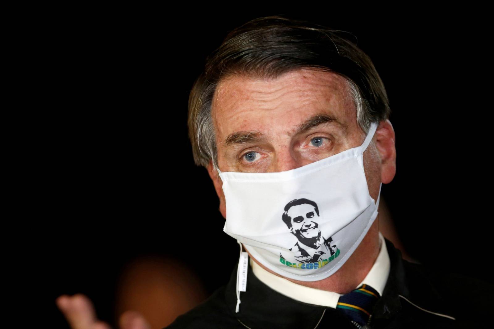 FILE PHOTO: Brazil's President Jair Bolsonaro speaks with journalists while wearing a protective face mask as he arrives at Alvorada Palace, amid the coronavirus disease (COVID-19) outbreak, in Brasilia