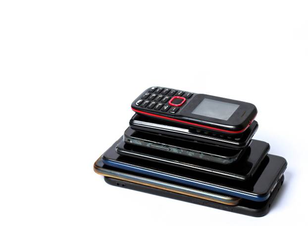 old mobile phones piled up on a table