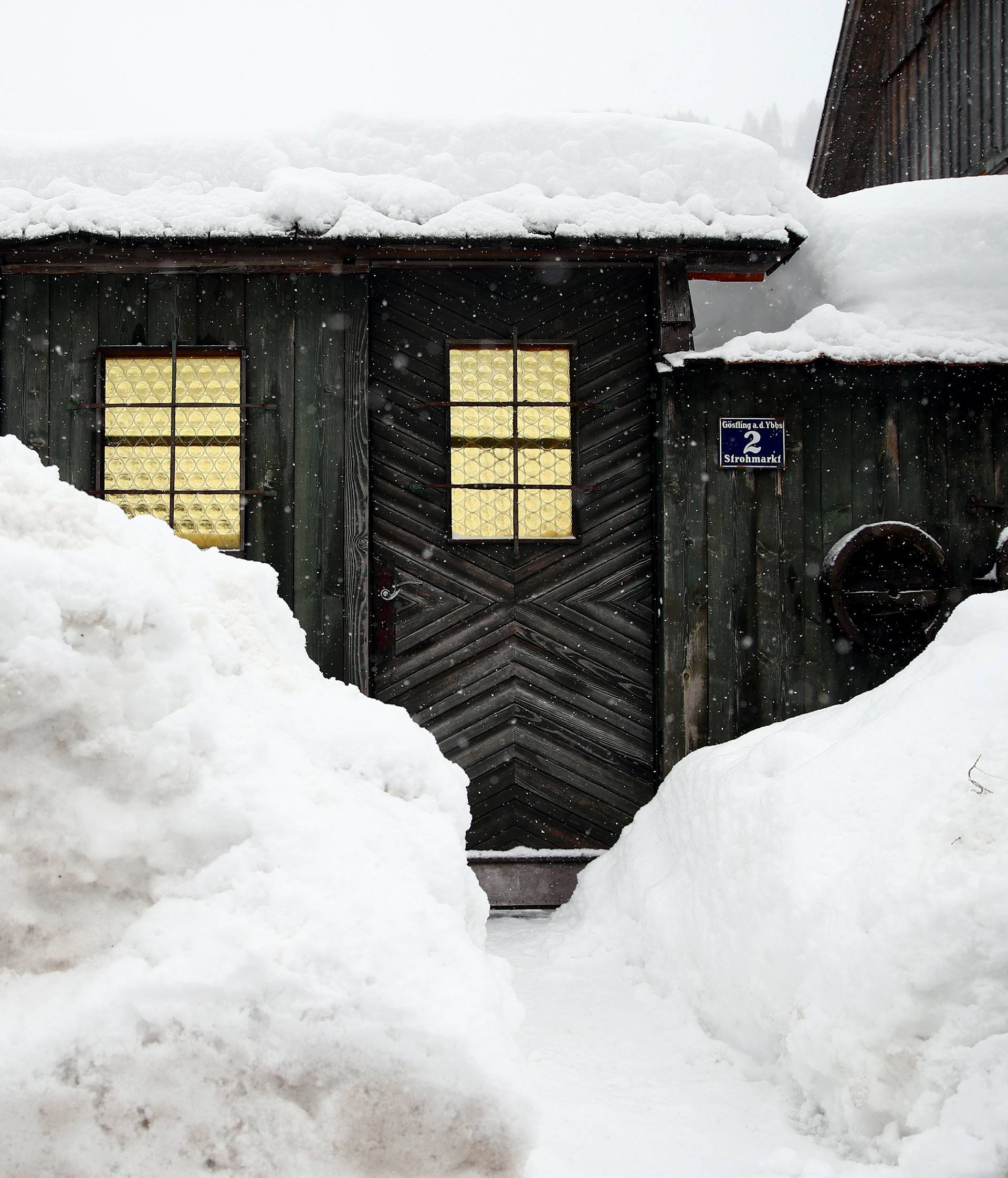 Snow partly blocks the entrance of a house during heavy snowfall in Goestling