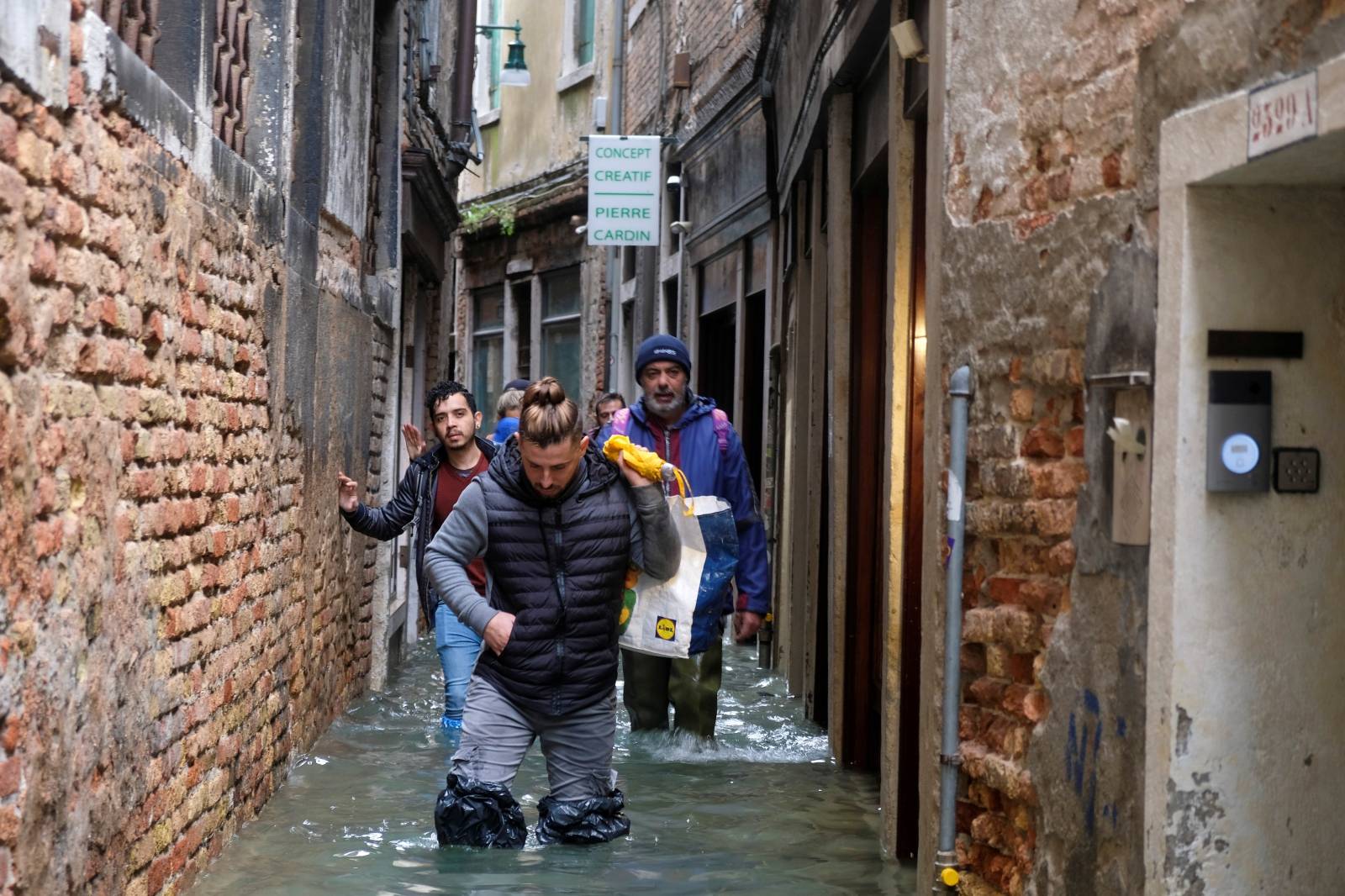 People walk in the flooded street during a period of seasonal high water in Venice