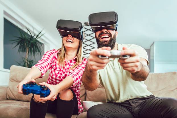 Happy friends playing video games with virtual reality glasses -