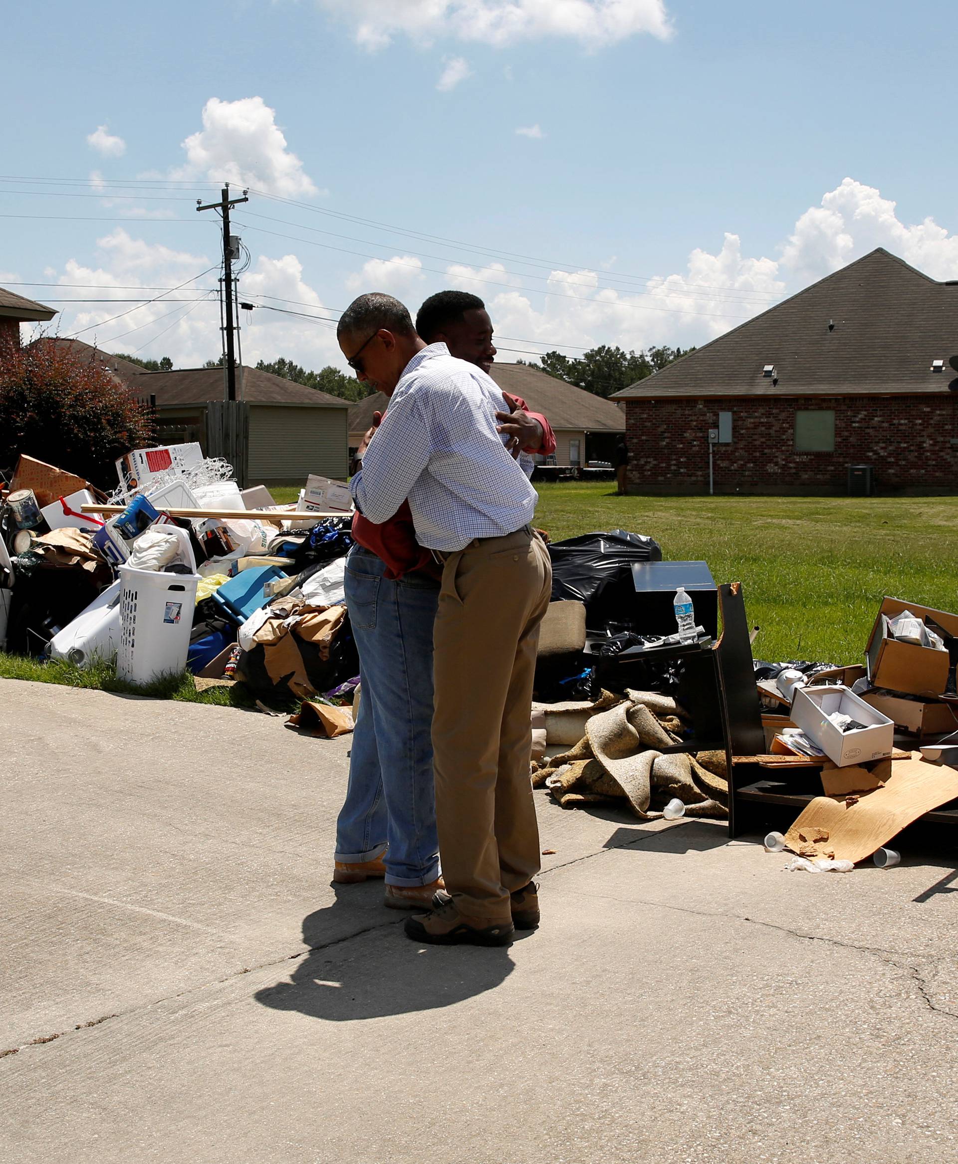U.S. President Barack Obama greets a homeowner as he tours a flood-affected neighborhood in Zachary