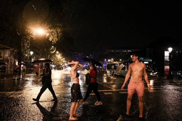 Tourists walk on a pedestrian crossing during a heavy rain in Barcelona
