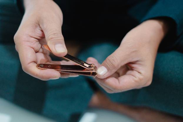 Close-up of person using nail clippers on fingernail, grooming and personal hygiene routine