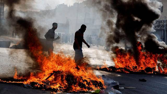 Palestinians take part in a protest following Israeli strikes on Gaza, in Nablus
