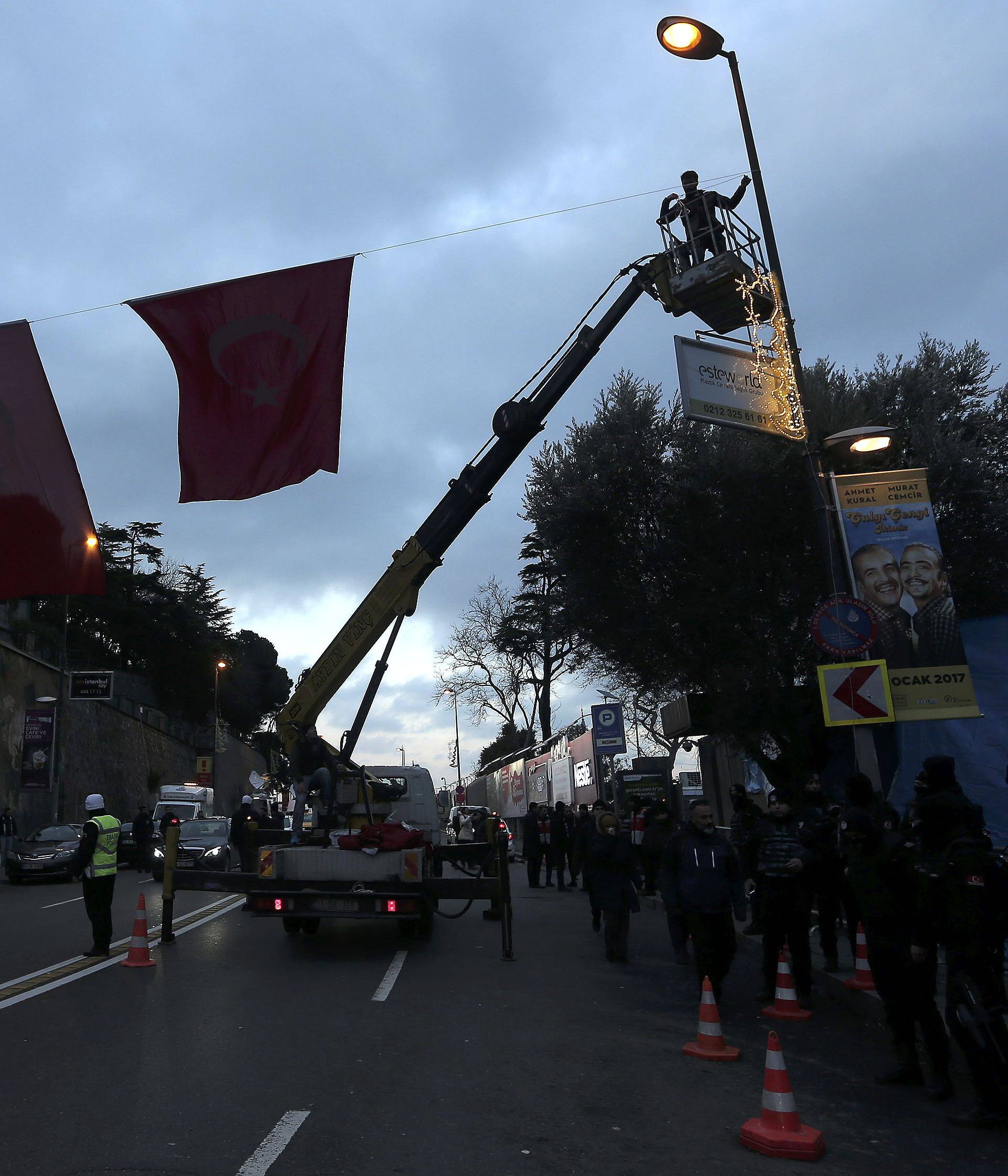 Worker attaches Turkish flags near the Reina nightclub by the Bosphorus, which was attacked by a gunman, in Istanbul