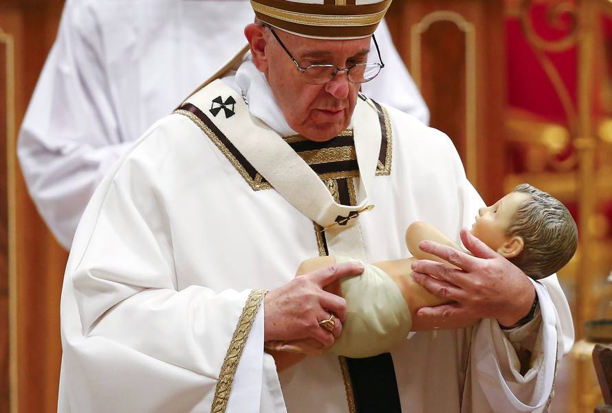 Pope Francis holds a statue of baby Jesus during the Christmas night Mass in Saint Peter's Basilica at the Vatican