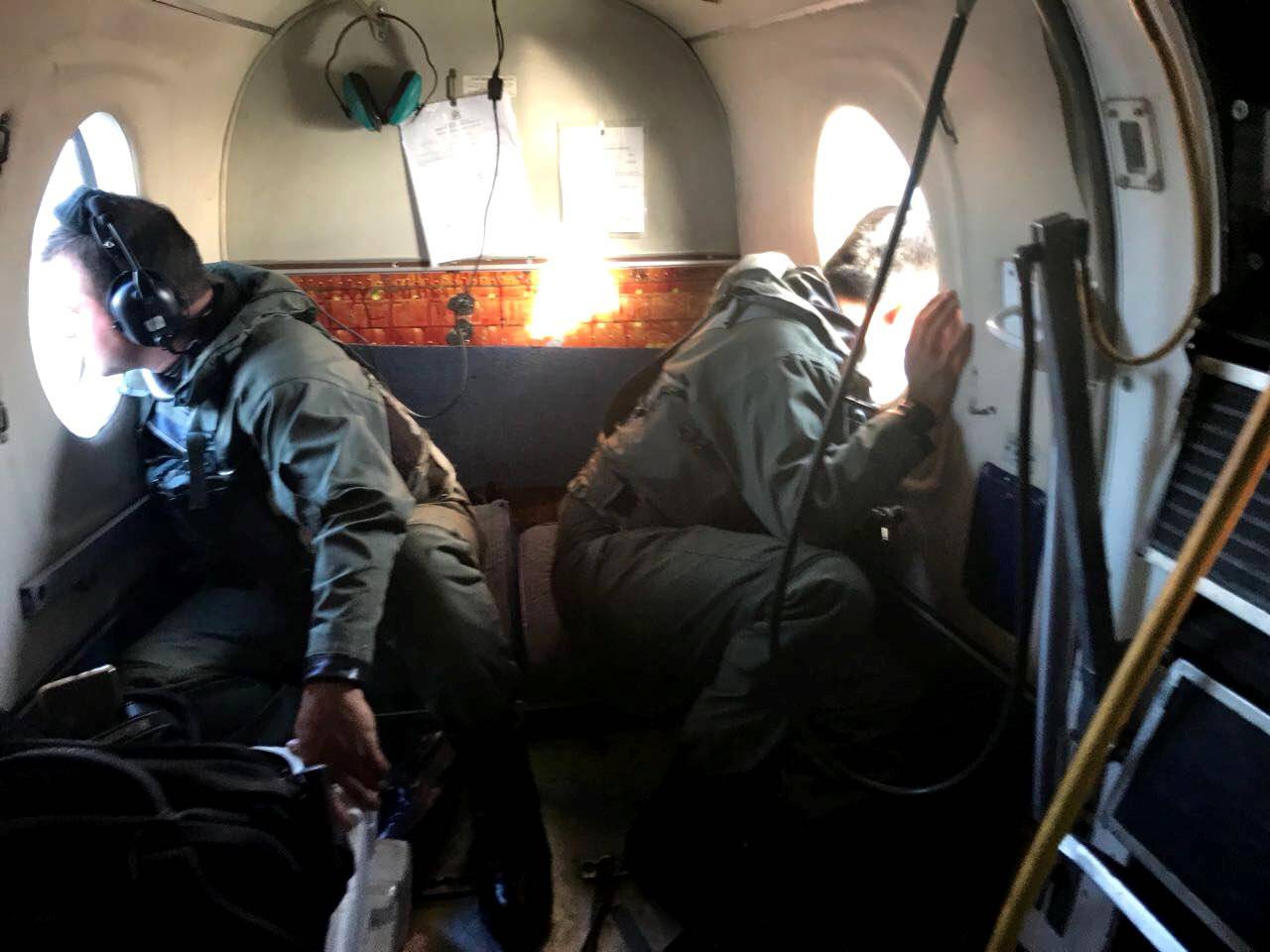 Members of the Argentine Navy look down at the sea from an airplane during a flight to search for the ARA San Juan submarine missing at sea