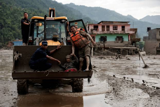 A survivor is transported to a safer place in heavy machinery following a flash flood at Trishuli, Nepal