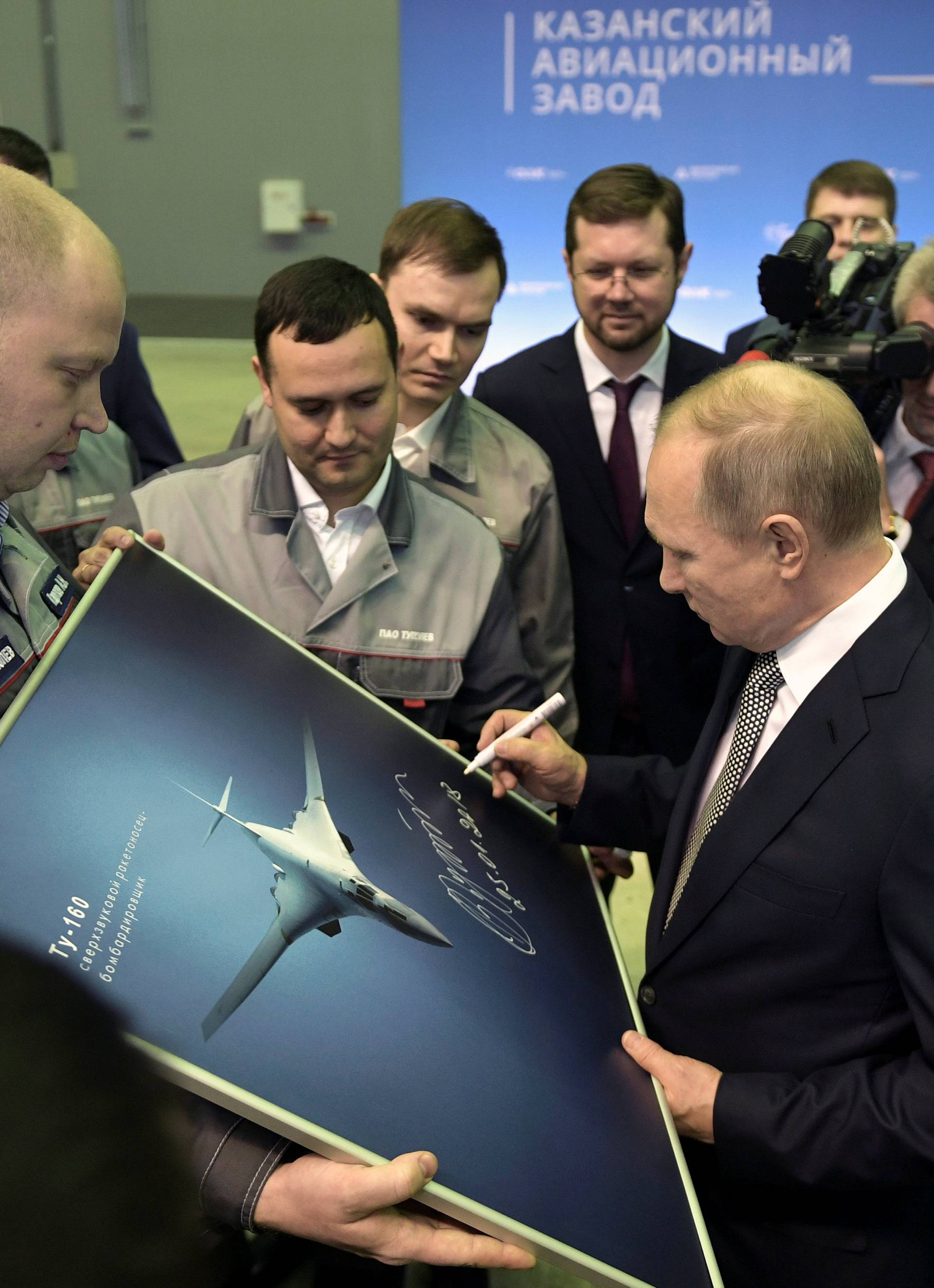 Russian President Vladimir Putin signs a picture of a TU-160M nuclear bomber during a visit to the Gorbunov Aviation factory in Kazan