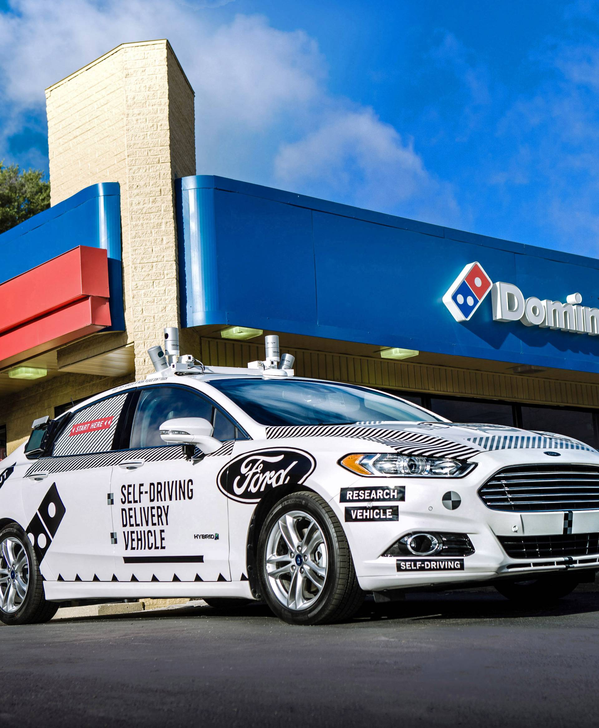 A Ford self-driving delivery vehicle is pictured in front of a Domino's pizza restaurant in this handout photo