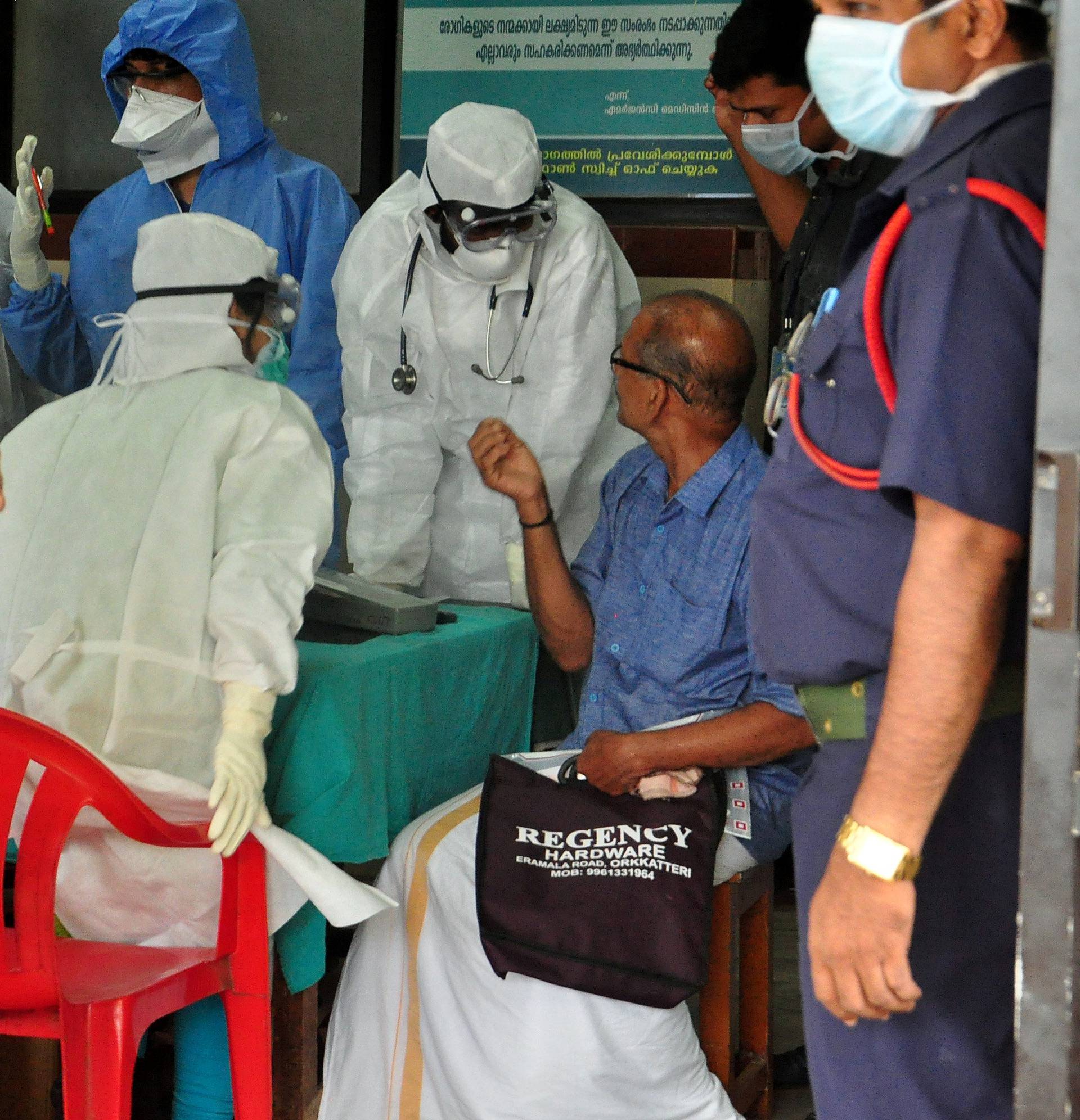 Medics wearing protective gear examine a patient at a hospital in Kozhikode in the southern state of Kerala