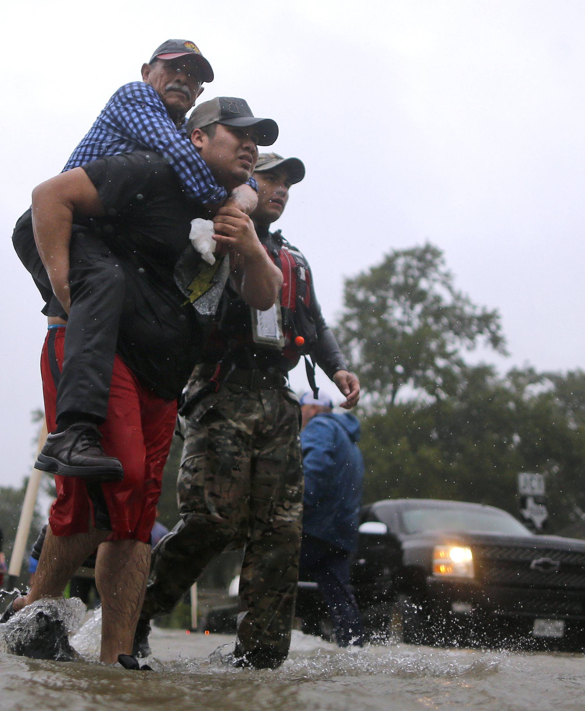 An elderly man is carried after being rescued from the flood waters of tropical storm Harvey in east Houston