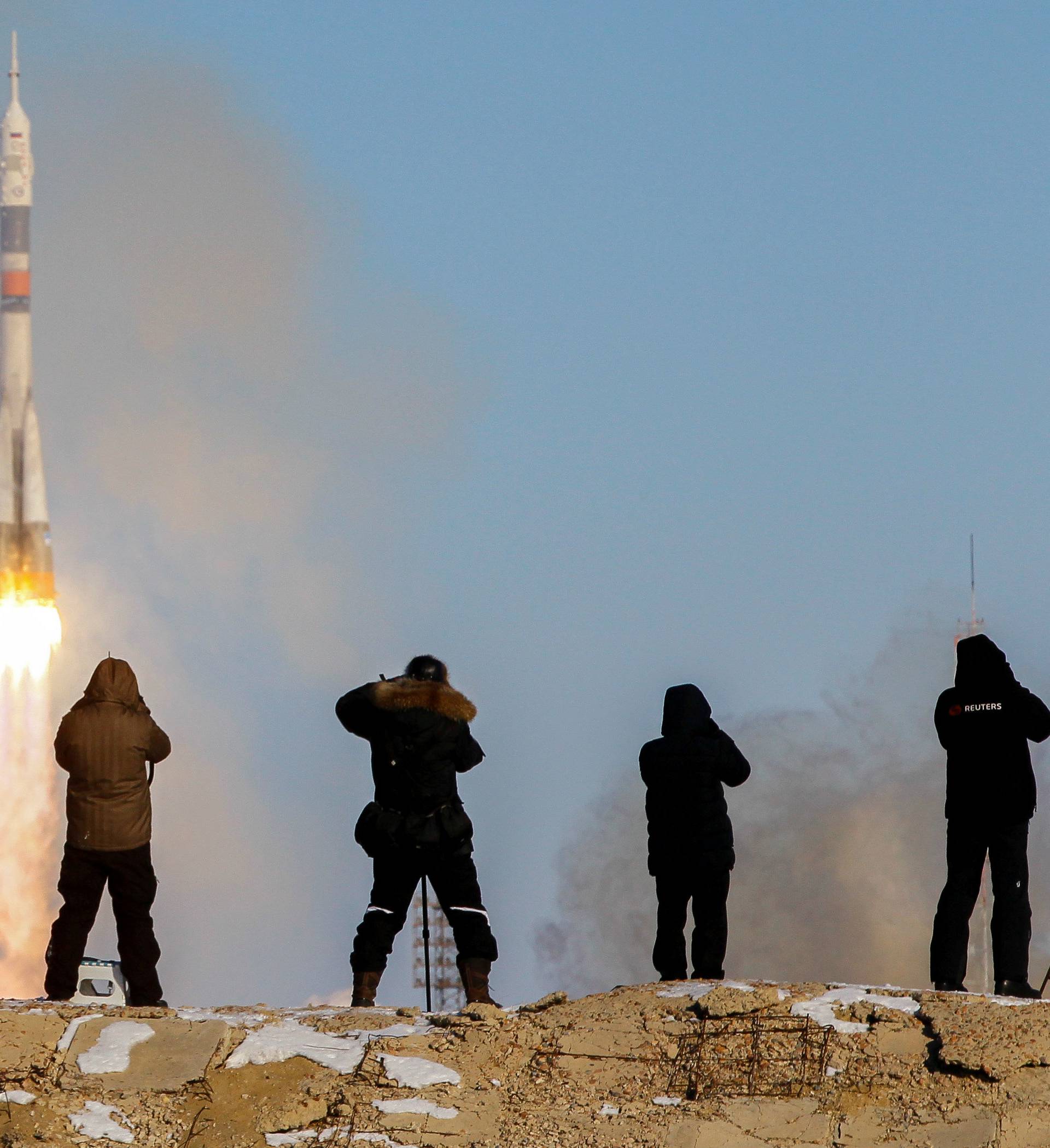 Photographers take pictures as the Soyuz MS-07 spacecraft carrying the next International Space Station (ISS) crew blasts off from the launchpad at the Baikonur Cosmodrome