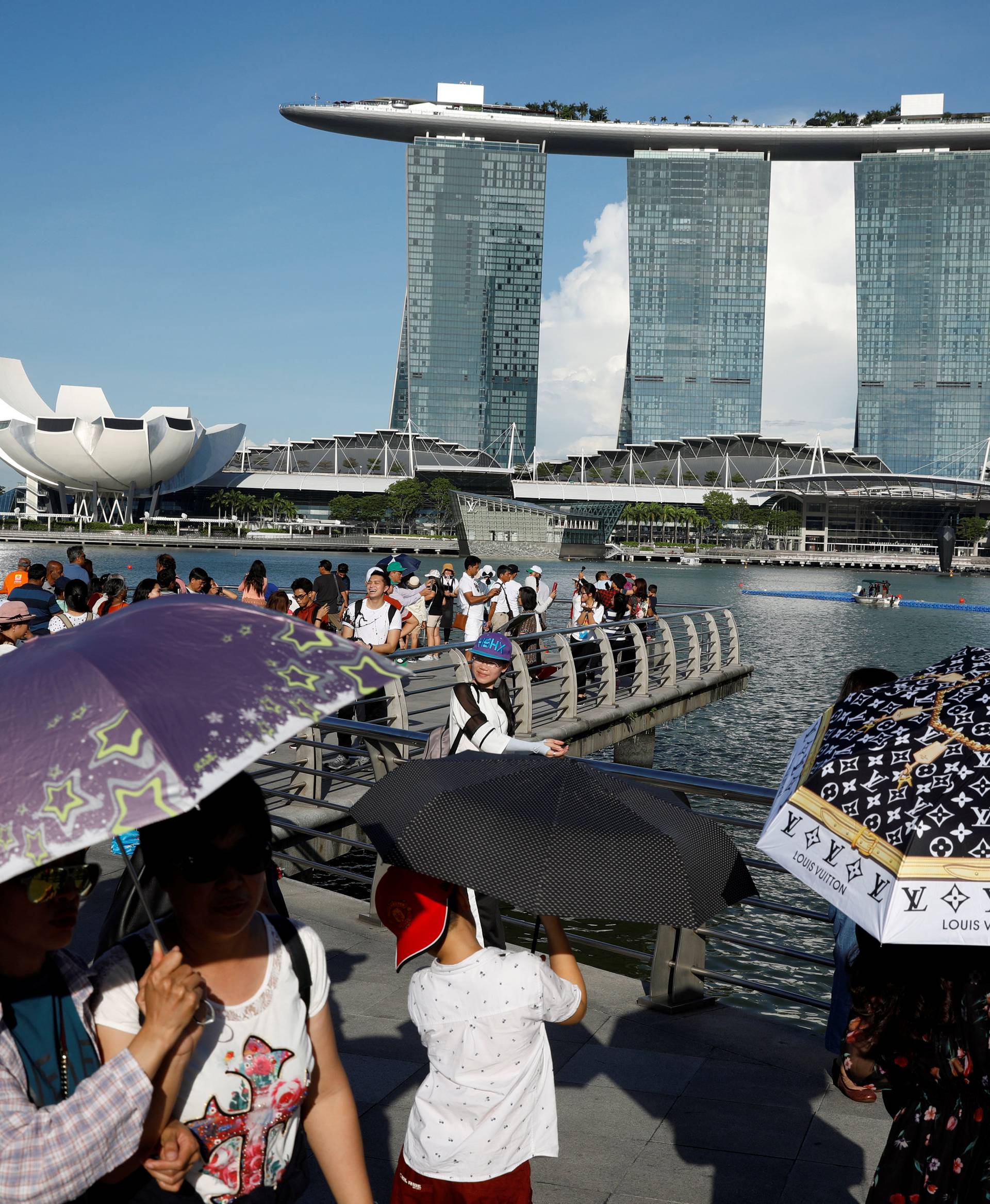 Tourists shield themselves with umbrellas from the sun in Singapore