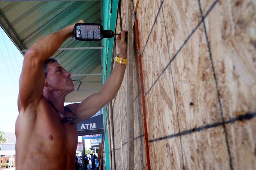 A man puts plywood up on the windows of his store before Hurricane Florence comes ashore in Wrightsville Beach