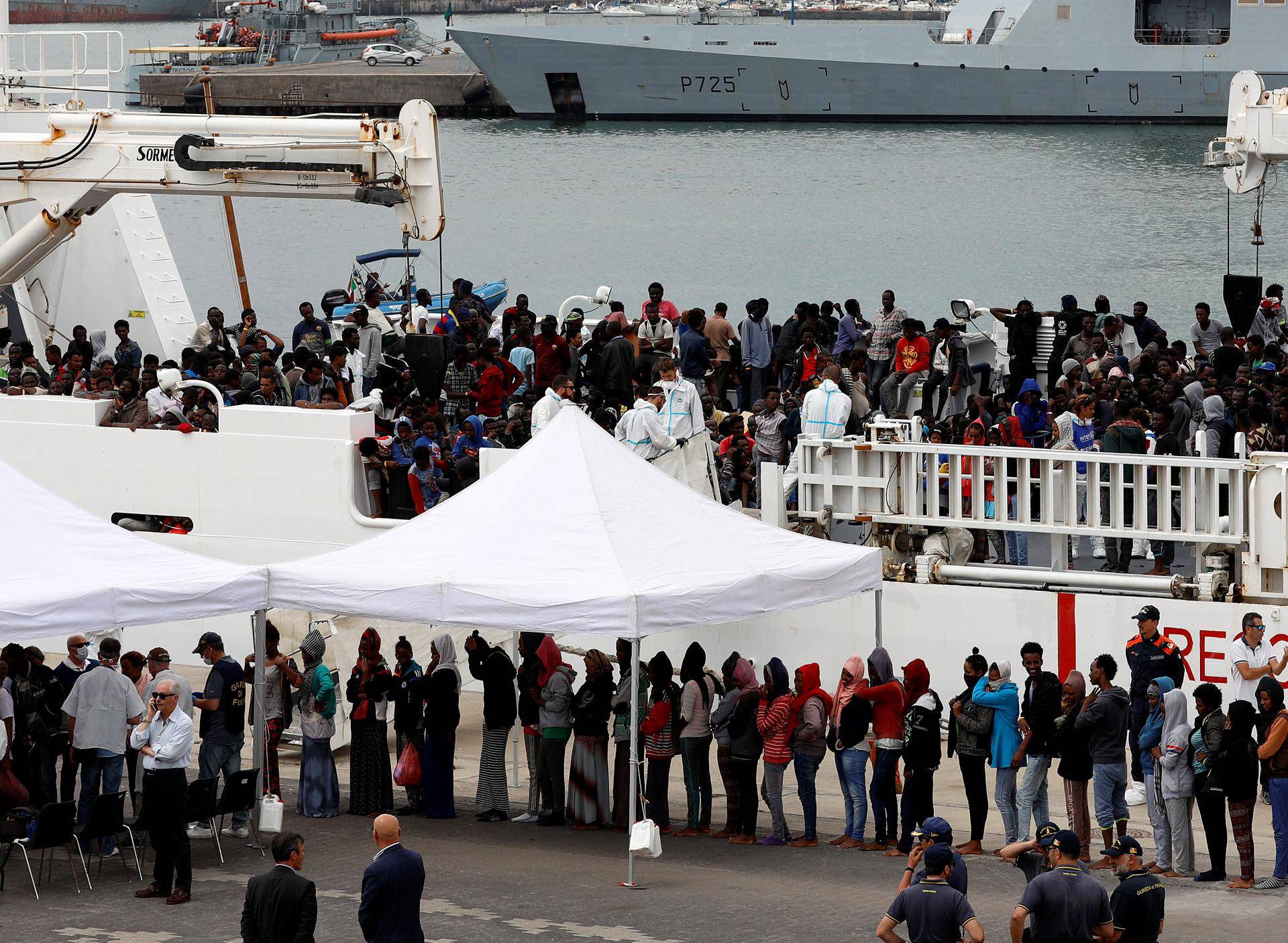 Migrants disembark Italian coast guard vessel "Diciotti" as they arrive at the port of Catania