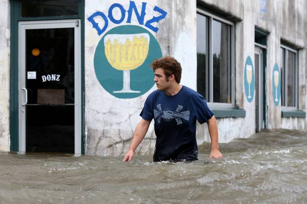 Logan Courvlle walks in front of a flooded business after Hurricane Barry in Mandeville