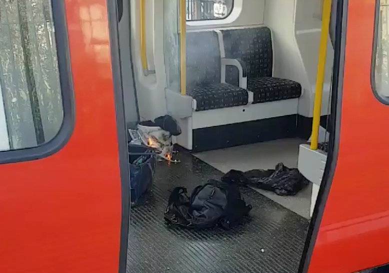 Personal belongings and a bucket with an item on fire inside it, are seen on the floor of an underground train carriage at Parsons Green station in London