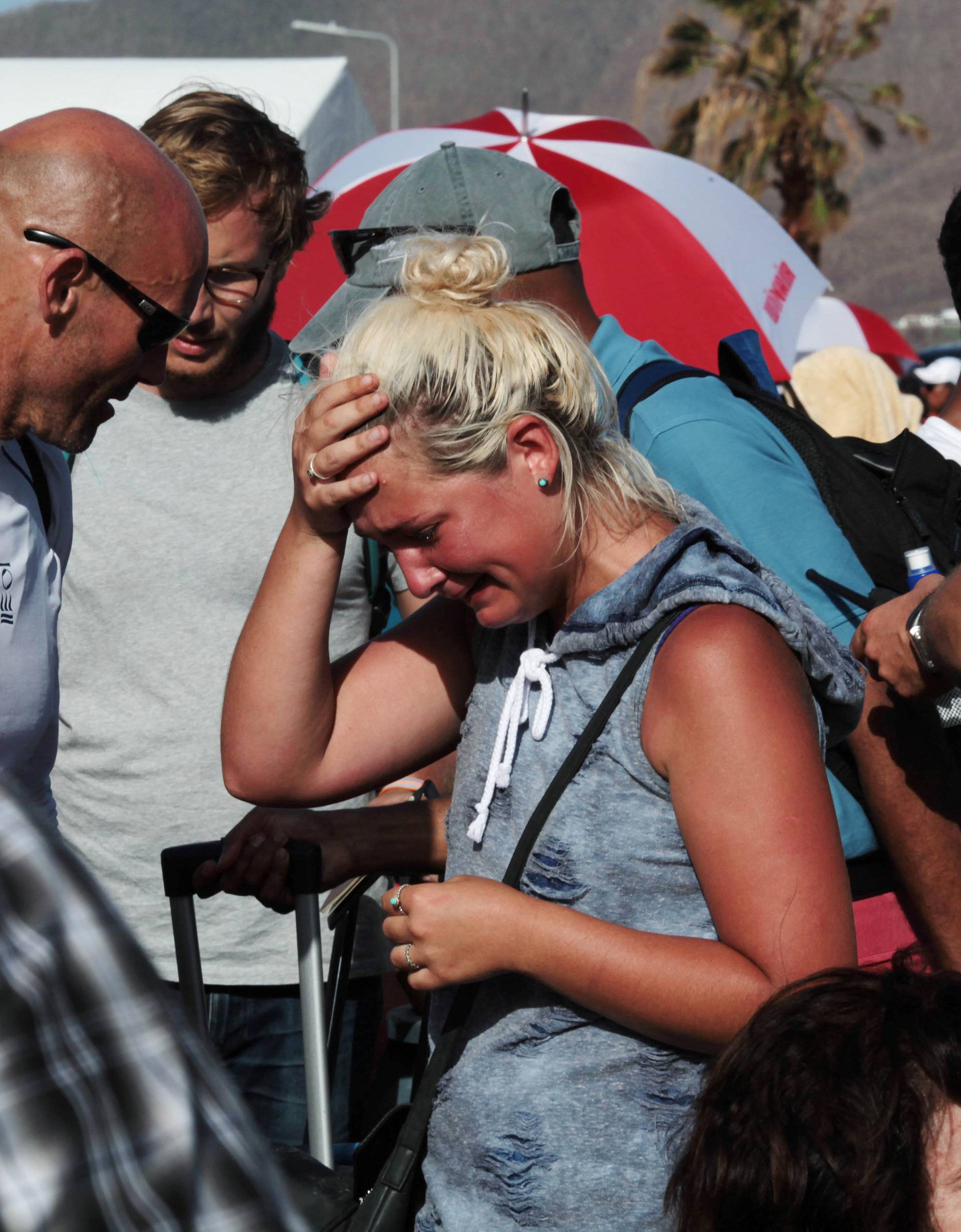 A woman reacts as she stands with others in line to board a plane and leave the island after it was devastated by Hurricane Irma, in Simpson Bay