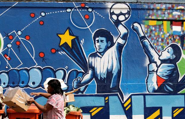 FILE PHOTO: A resident stands near a mural depicting the famous "Hand of God" goal by former Argentine soccer star Diego Maradona, in Rio de Janeiro
