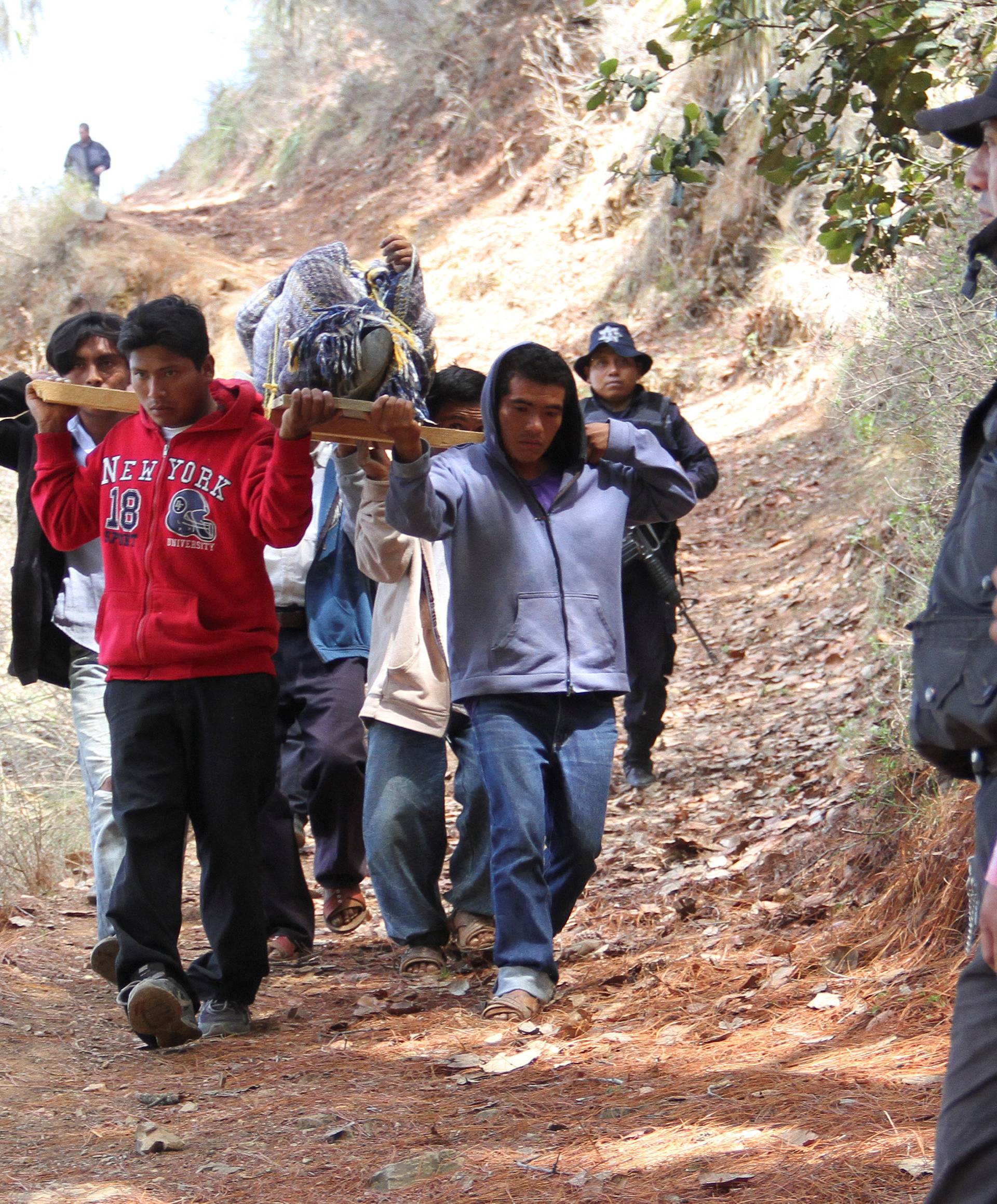 Residents carry the body of one of the victms of an armed attack as police officers guard the perimeter of a crime scene in Coxcatlan