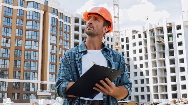 Builder,In,Hard,Hat,Holding,Clipboard,On,Construction,Site